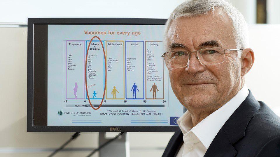 Inventeur qui sourit devant un écran projetant des informations sur les vaccins 