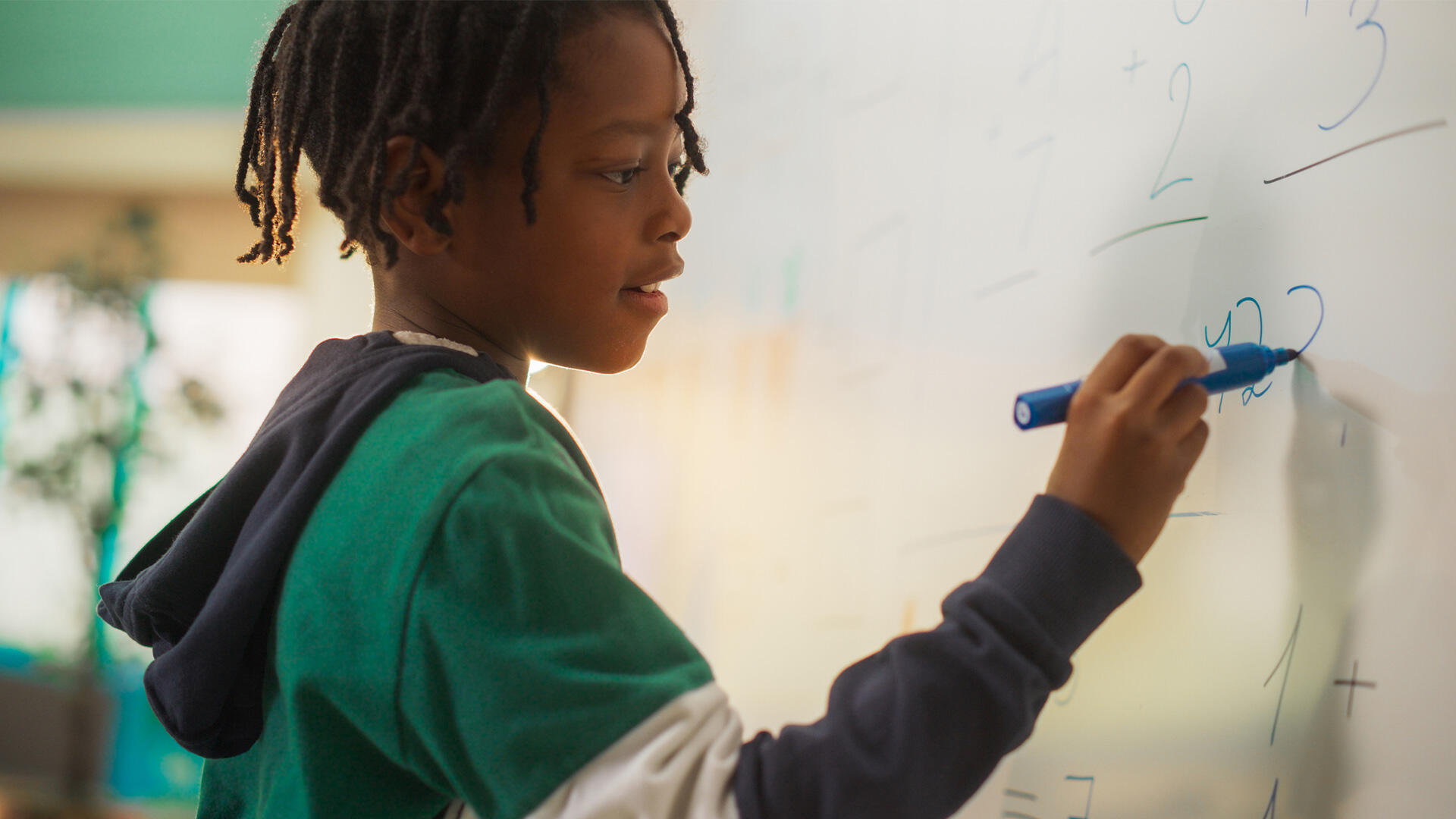Kid at the chalkboard writing numbers
