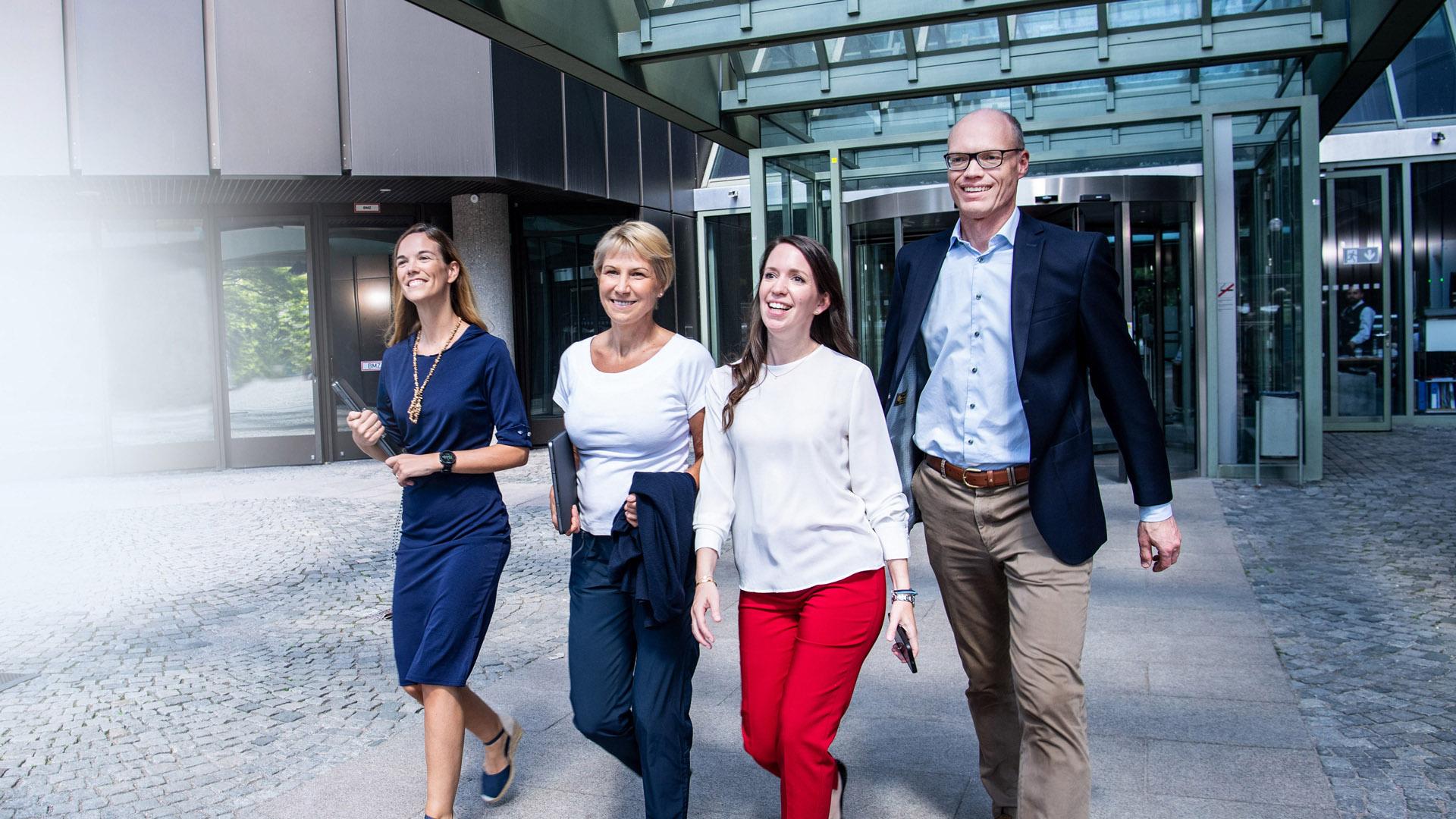 Four smiling people walk out of the EPO's Isar building