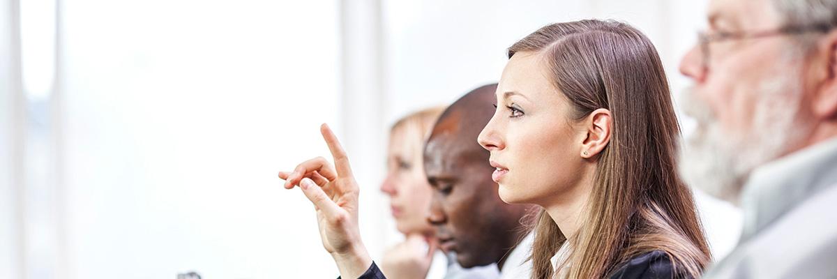 A woman raises her hand to speak in a meeting